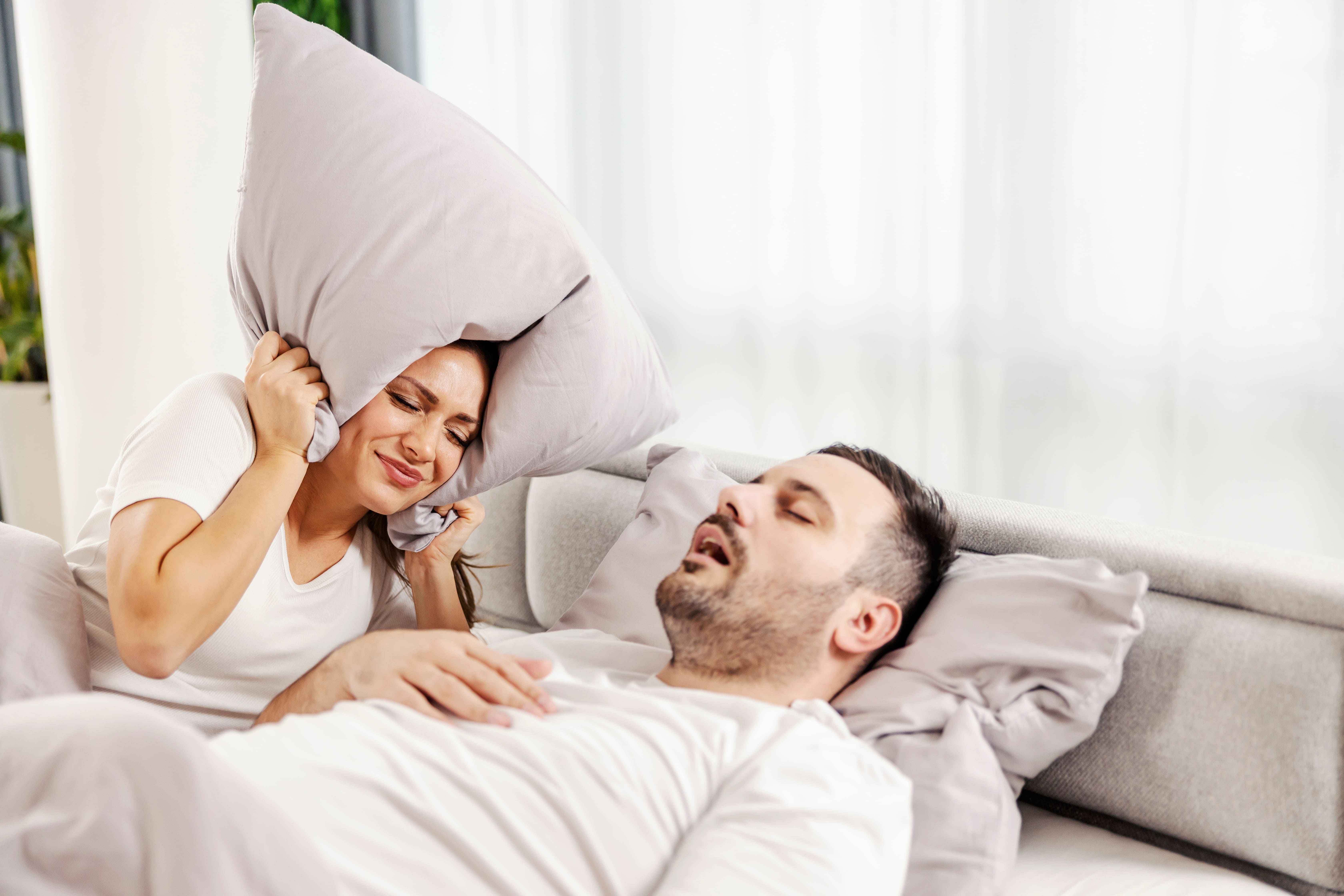 Homem dormindo roncando e sua esposa incomodada
