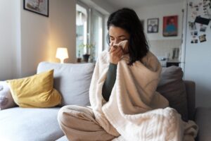 Moça coberta e assoando o nariz por causa do frio