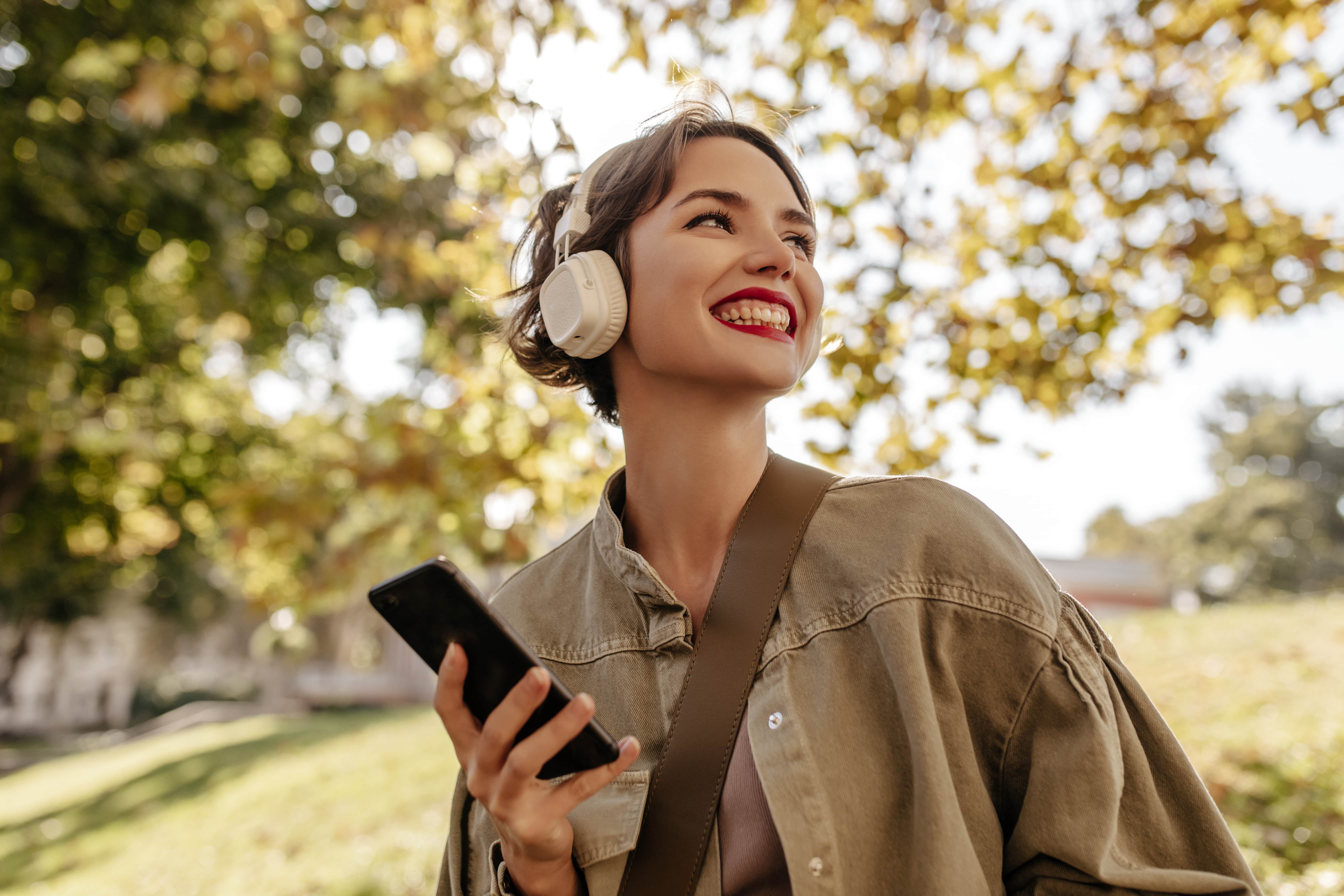Mulher com fone de ouvido ouvindo música e segurando o celular